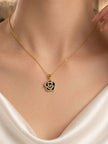 Model wearing gold-plated black enamel rose pendant necklace over a white satin outfit