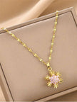 Gold-plated snowflake pendant necklace with pink cubic zirconia stones displayed in a beige jewellery box