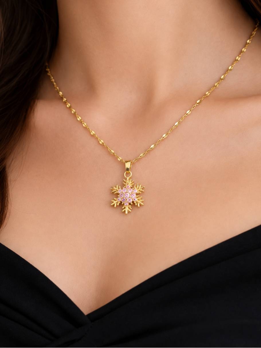 Model wearing gold snowflake pendant necklace on a twisted Singapore chain over a black top