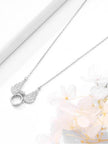 Close-up of angel wings pendant necklace resting on white surface with flowers