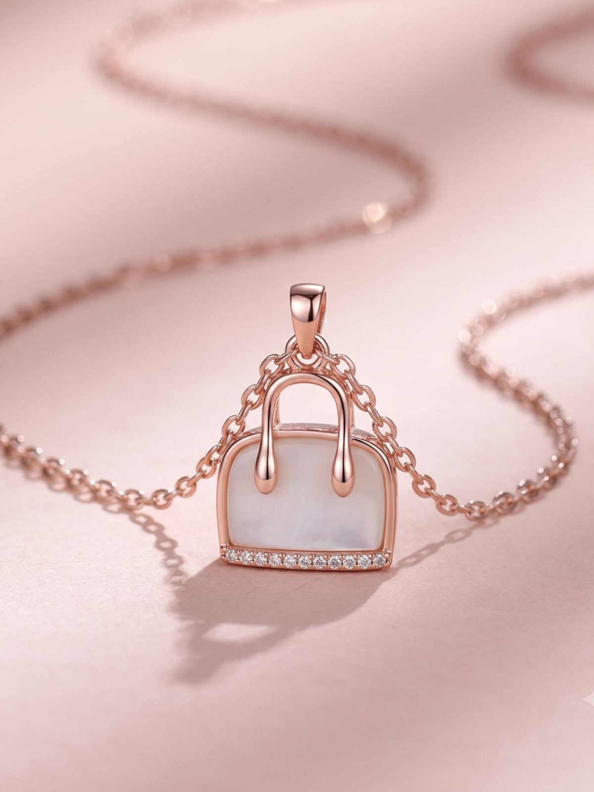 Close-up of rose gold handbag pendant with mother of pearl inlay on pink surface