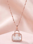 Full view of rose gold satellite chain necklace with handbag pendant on pink background