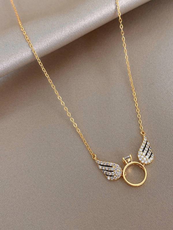 Gold-plated angel wings ring charm necklace laid flat on a beige fabric background