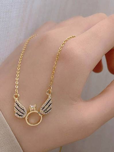 Angel wings ring charm necklace draped across the back of a hand for scale