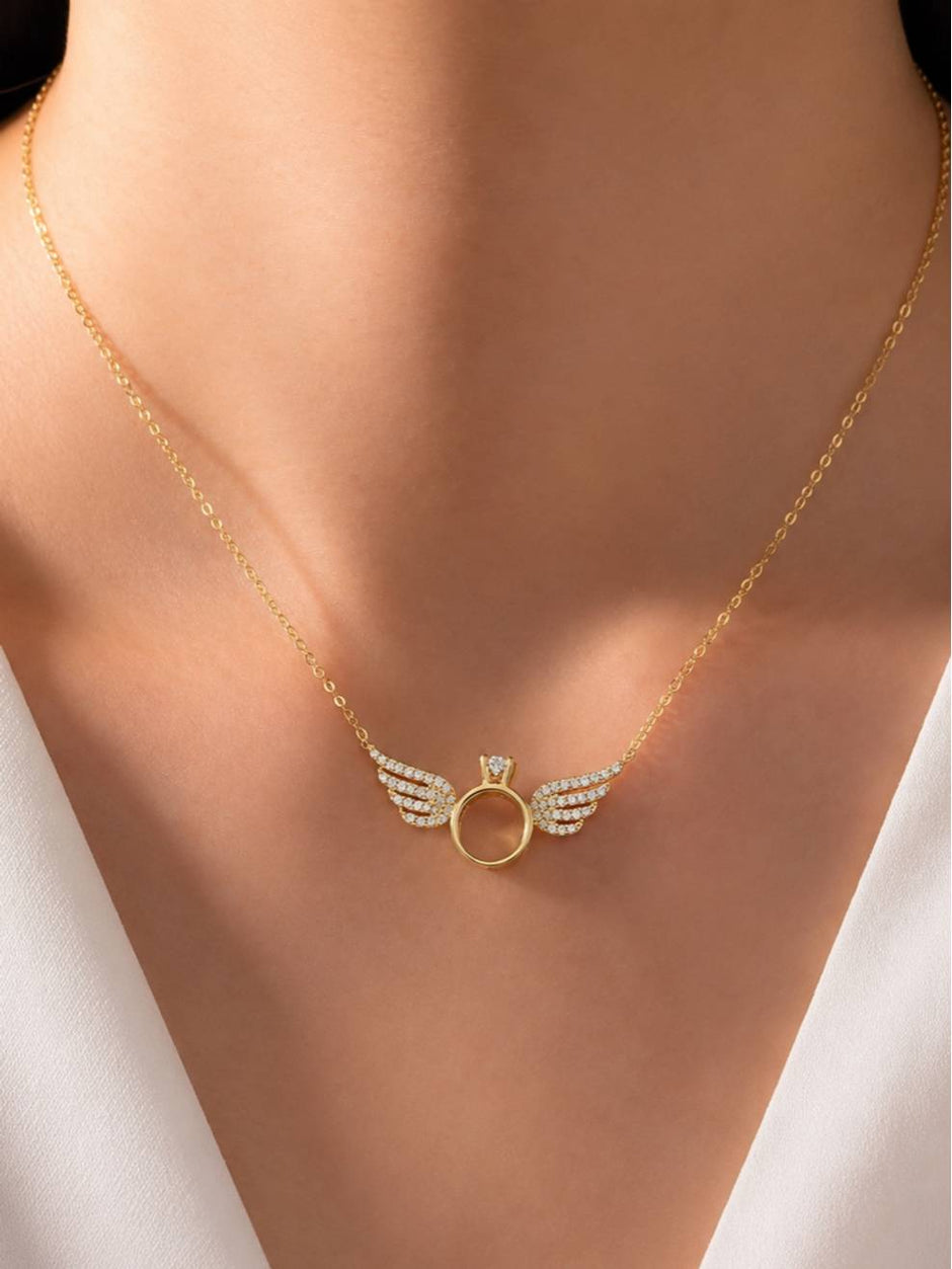 Gold angel wings ring necklace worn at the collarbone over a white outfit