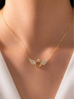 Gold angel wings ring necklace worn at the collarbone over a white outfit