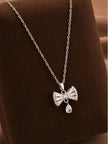 Silver bow pendant necklace with cubic zirconia stones displayed on a brown velvet jewellery tray