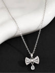 CZ bow necklace laid flat on a black and white marble surface showing full chain length