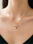 Crystal bow pendant necklace worn on a model's neckline over a black top