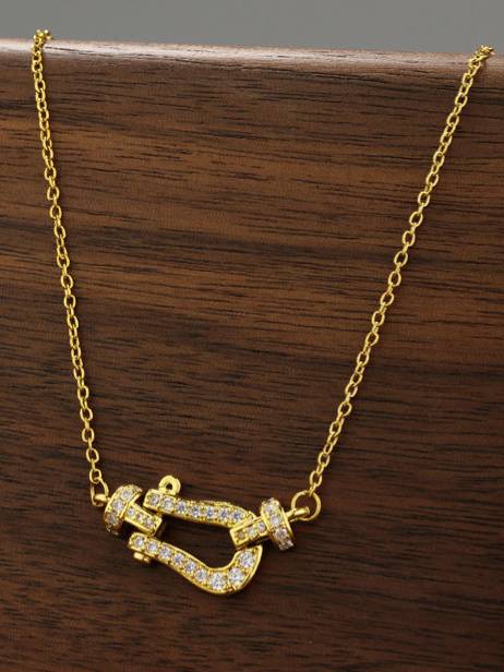 Gold-plated CZ horseshoe clasp necklace displayed on a wooden surface showing full pendant detail