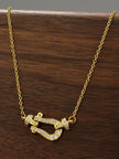 Gold-plated CZ horseshoe clasp necklace displayed on a wooden surface showing full pendant detail