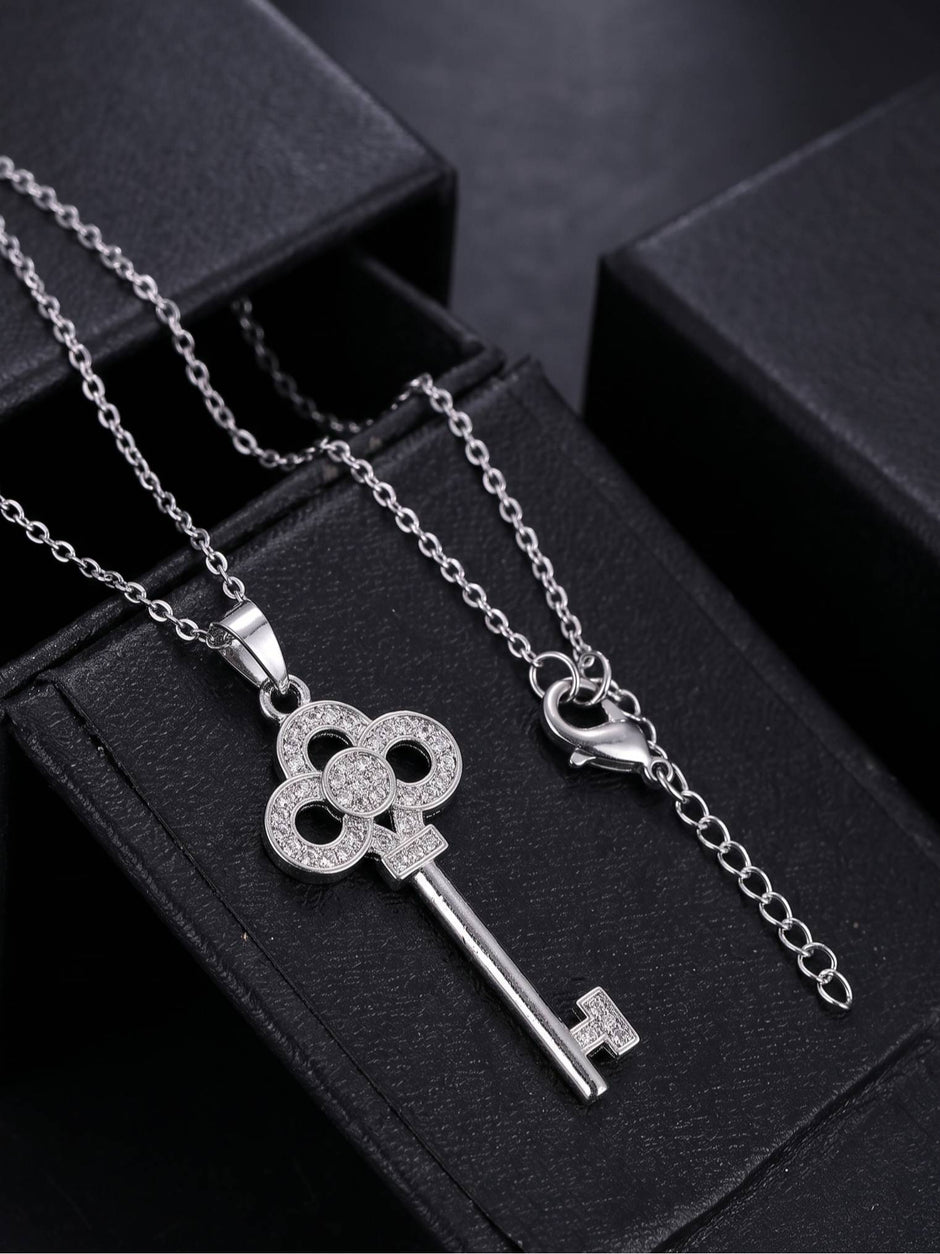 Key pendant necklace with lobster clasp and extender chain laid out on black jewellery boxes