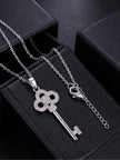 Key pendant necklace with lobster clasp and extender chain laid out on black jewellery boxes