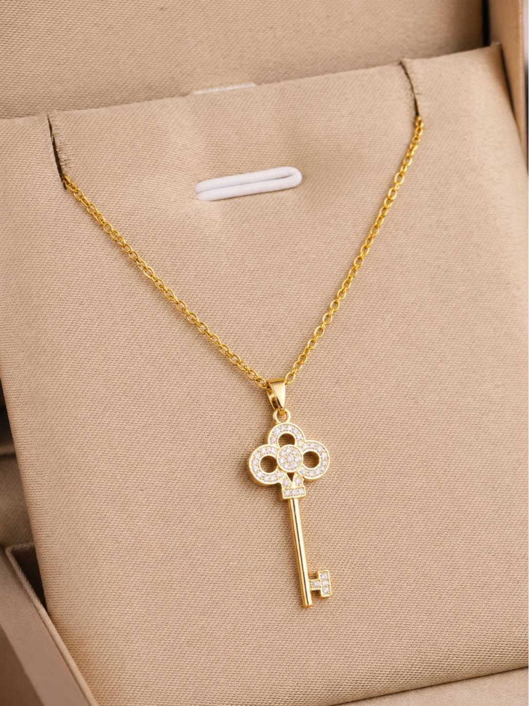 Gold-plated CZ key pendant necklace displayed inside a beige gift box