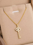 Gold-plated CZ key pendant necklace displayed inside a beige gift box
