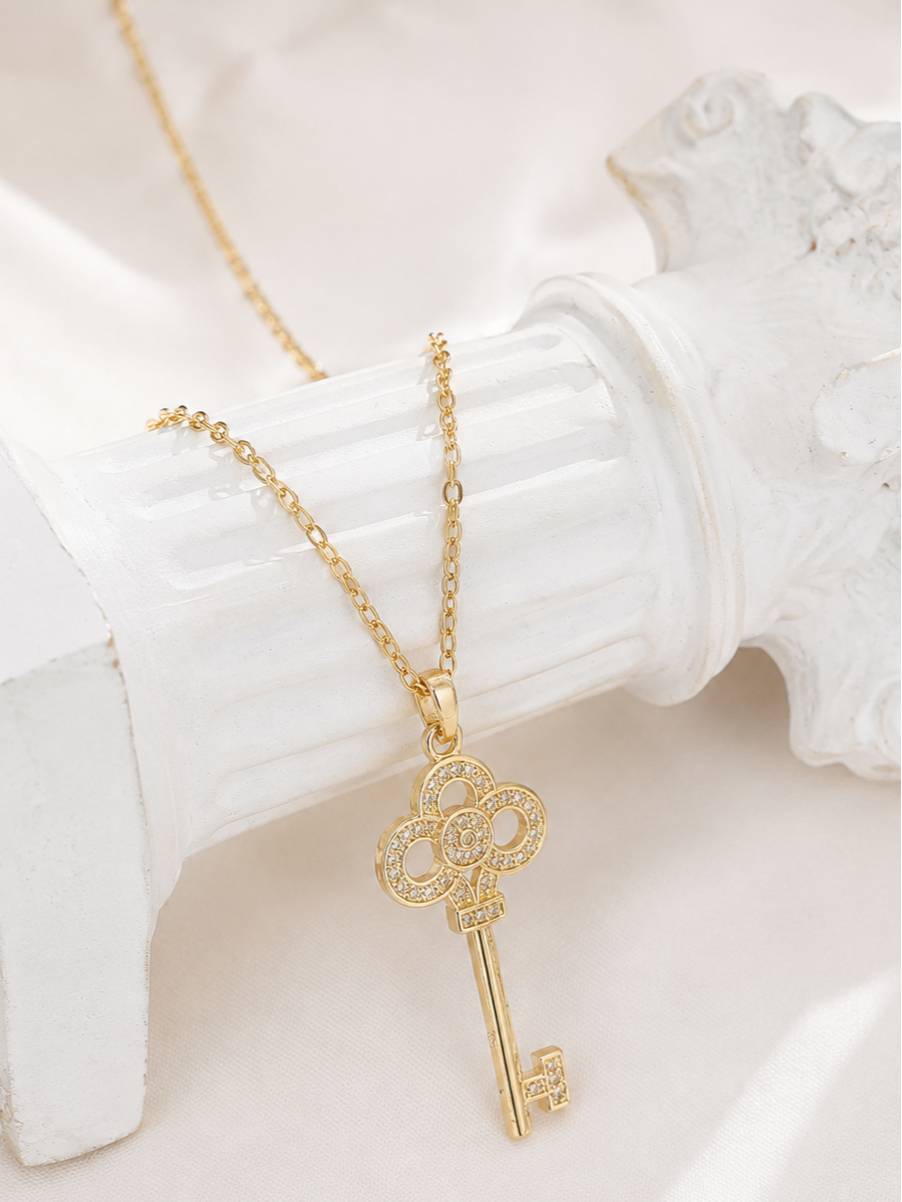 Key pendant necklace with cubic zirconia stones resting on a white plaster stand