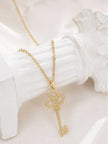 Key pendant necklace with cubic zirconia stones resting on a white plaster stand