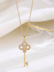 Close-up of gold-plated trefoil key pendant with CZ setting on white fabric