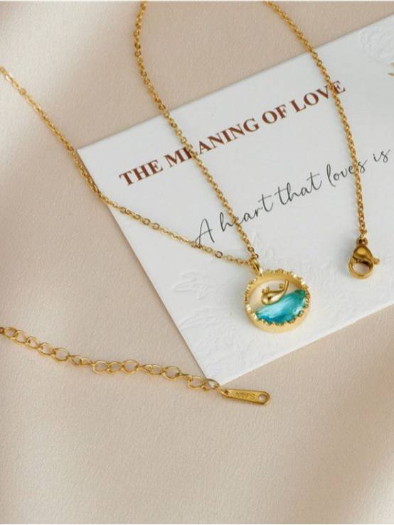 Ocean wave pendant necklace laid flat on gift card reading The Meaning of Love with lobster clasp visible