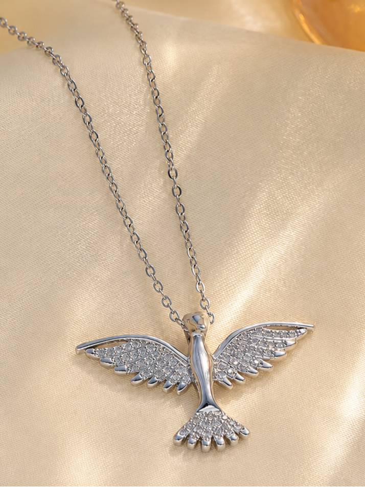 Close-up of silver bird pendant with cubic zirconia wings on cream satin fabric