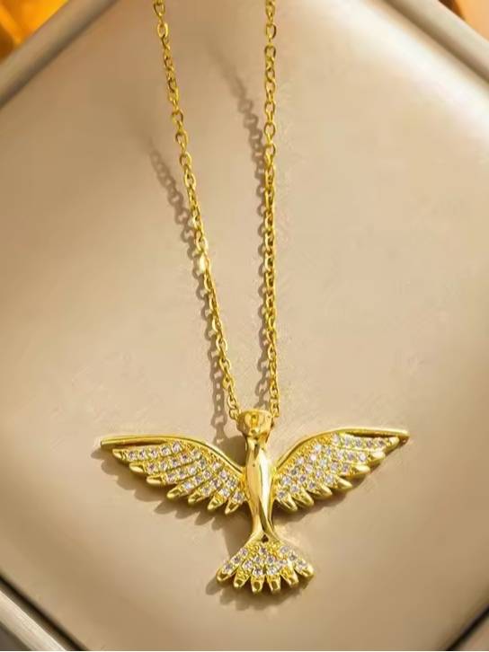 Gold-plated soaring bird pendant necklace with cubic zirconia wings displayed on a cream jewellery tray