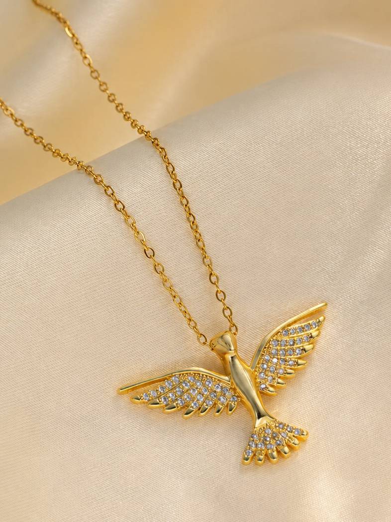 Close-up of gold bird pendant with crystal-encrusted wings and tail on a cream satin fabric