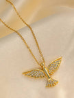 Close-up of gold bird pendant with crystal-encrusted wings and tail on a cream satin fabric