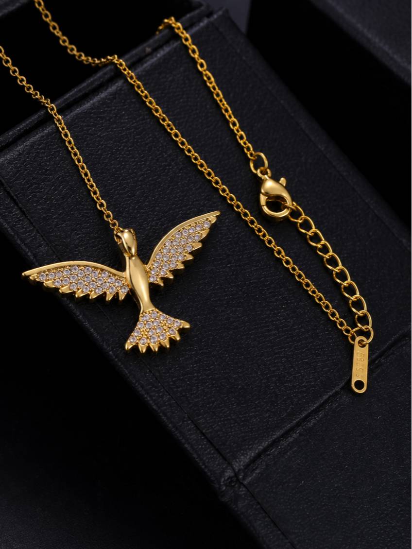 Flat lay of gold bird pendant necklace showing reverse side and lobster clasp extender chain on black velvet