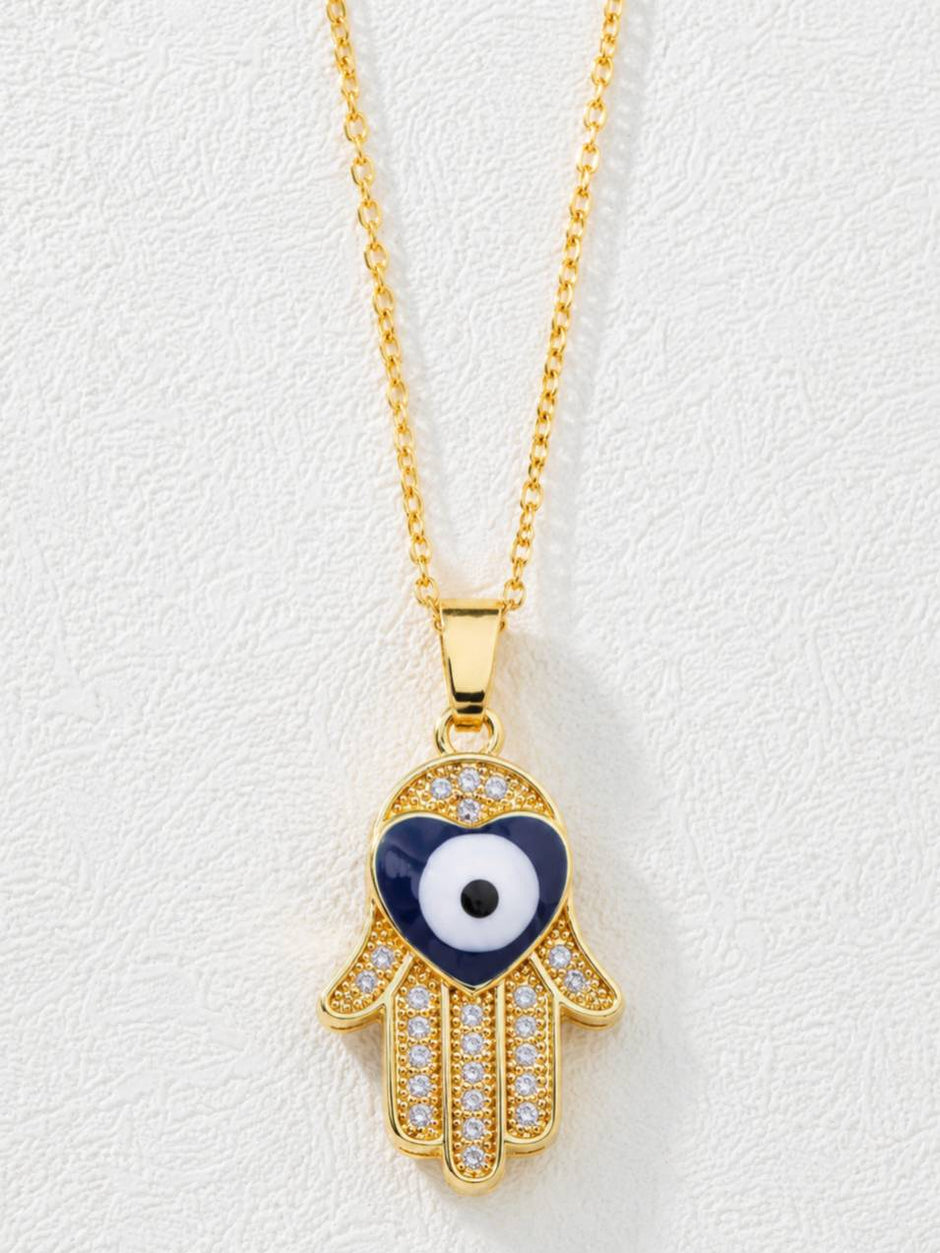 Close-up of Hamsa hand pendant with navy blue heart-shaped evil eye and cubic zirconia stones on white background