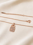 Rose gold cable chain necklace laid flat showing lobster clasp, extender chain and bag charm pendant