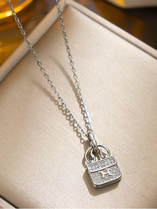 Silver zirconia bag pendant necklace displayed in a cream jewellery box close up