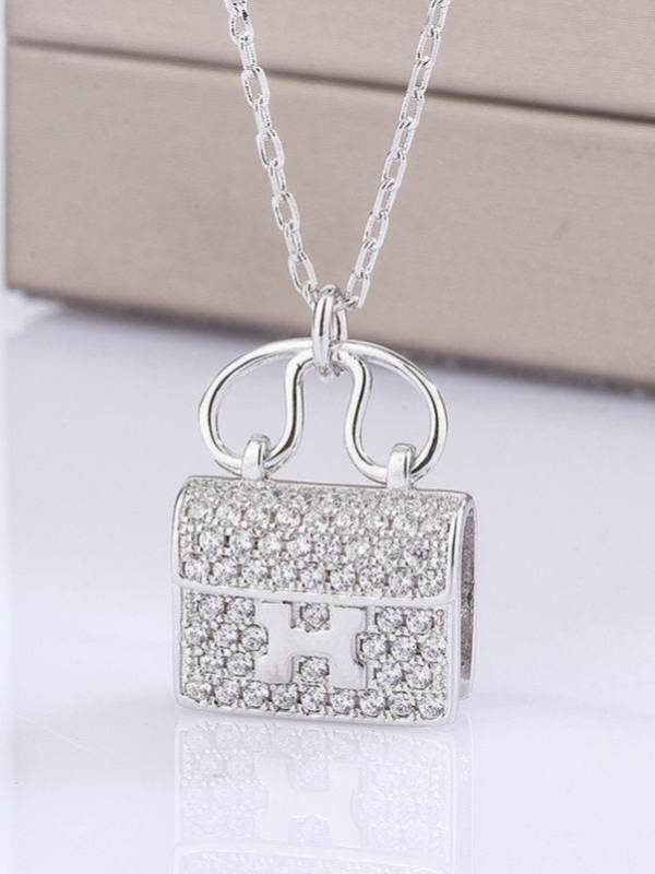Close-up of pave cubic zirconia bag pendant with H-lock detail on silver chain against white background