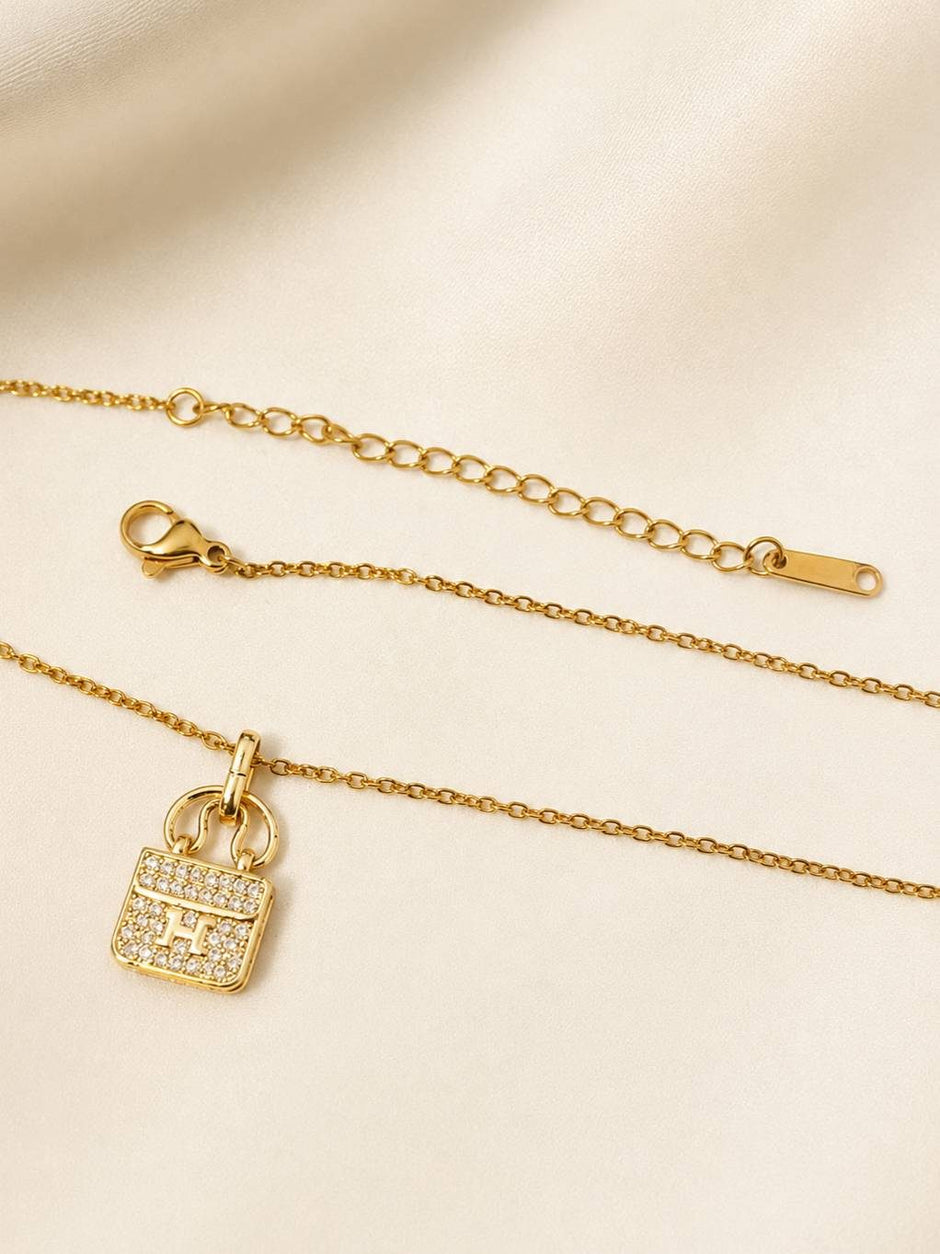 Flat lay of gold-plated bag charm necklace showing lobster clasp, extender chain and pavé pendant