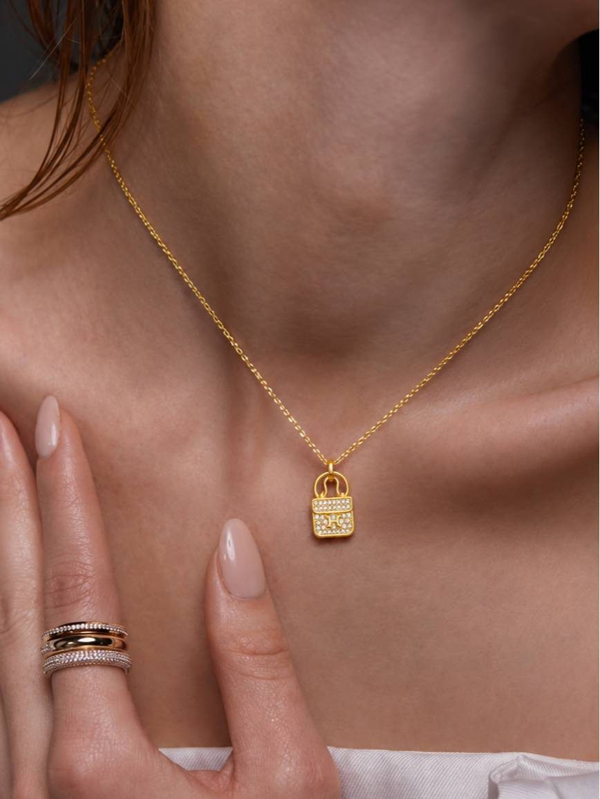 Woman wearing gold-plated bag pendant necklace at collarbone with stacked rings on hand