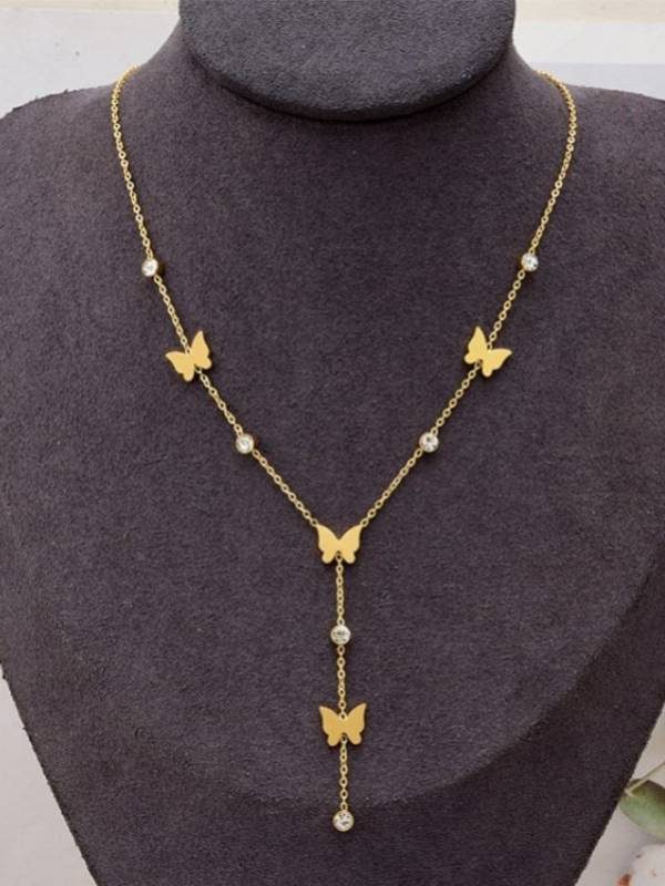 Gold-plated butterfly lariat necklace displayed on a dark jewellery bust, showing four butterfly charms and crystal rhinestones with a drop tail