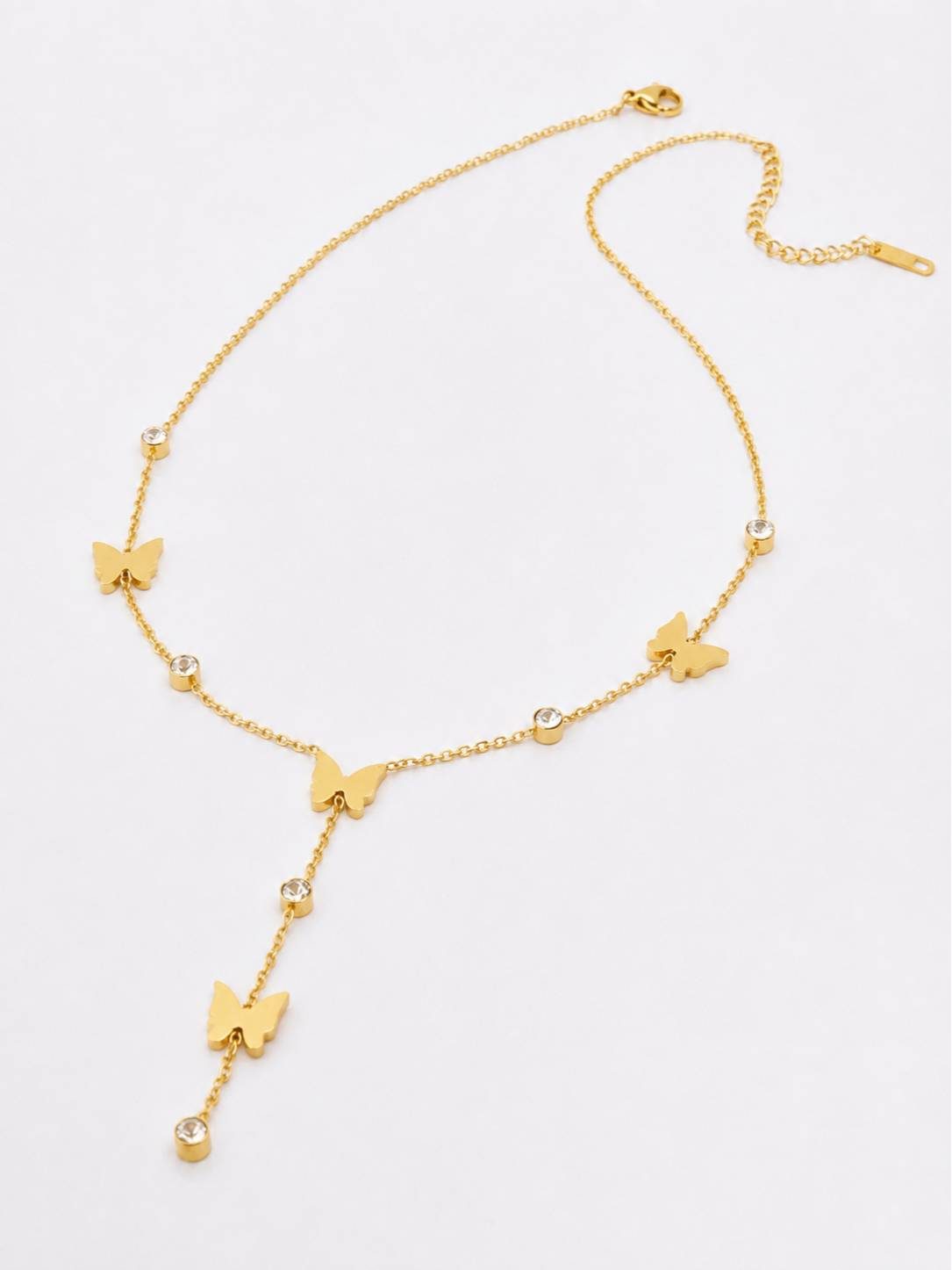Flat lay of gold butterfly lariat necklace on white background showing lobster clasp, butterfly charms, bezel-set rhinestones and pendant drop