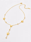 Flat lay of gold butterfly lariat necklace on white background showing lobster clasp, butterfly charms, bezel-set rhinestones and pendant drop