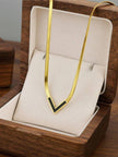 Gold herringbone V-shape necklace with black enamel pendant displayed in a wooden jewellery box
