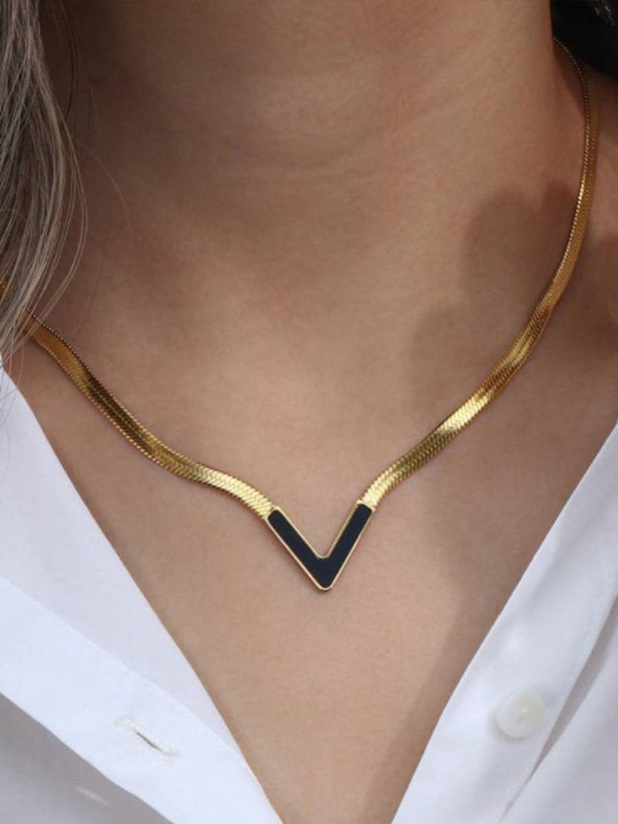 Gold-plated V-shape black enamel necklace worn on a woman's neck over a white button-down shirt