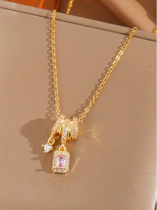 Gold-plated CZ charm necklace with pink halo pendant and round solitaire charm on beige background