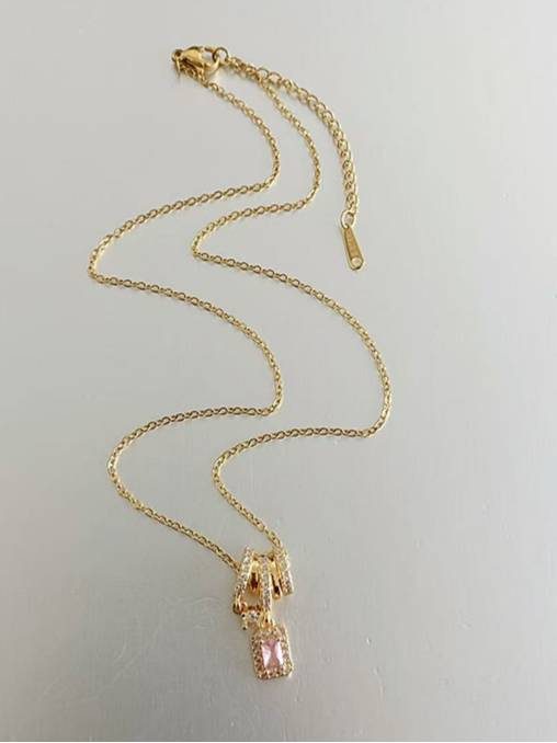 Full length view of gold-plated chain necklace with pink emerald-cut halo charm and lobster clasp on white surface
