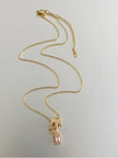 Full length view of gold-plated chain necklace with pink emerald-cut halo charm and lobster clasp on white surface