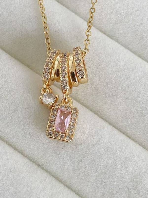 Close-up of triple pavé ring slider with dangling pink CZ halo pendant and clear solitaire charm on jewellery velvet tray