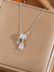 Silver pendant necklace with pink emerald-cut zirconia and round solitaire charm on beige jewellery tray
