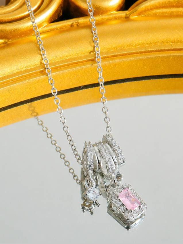 Silver pendant necklace with pink zirconia charm reflected in mirror against gold ornate frame