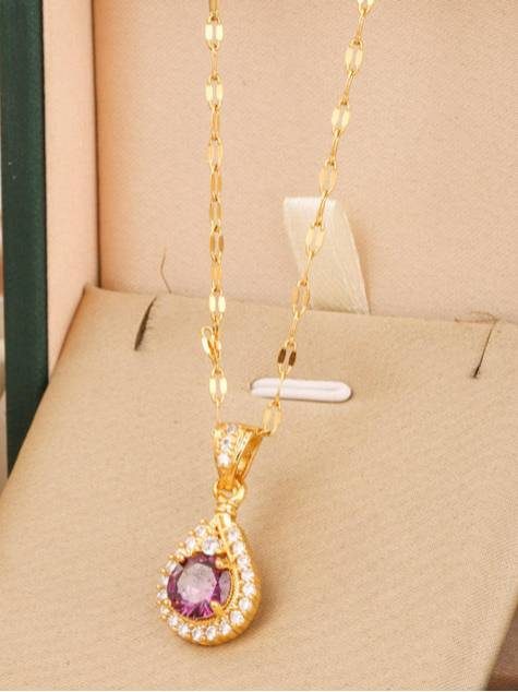 Gold-plated teardrop pendant necklace with purple CZ stone displayed in a cream jewellery box