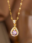 Close-up of gold-plated halo teardrop pendant with purple and white cubic zirconia stones hanging freely