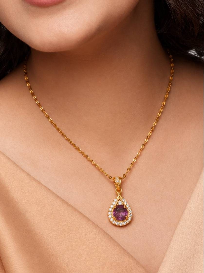 Gold-plated amethyst-tone CZ halo pendant necklace on a tan fabric background with a white flower accent
