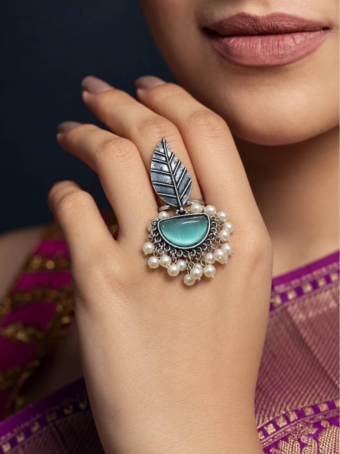 Oxidised silver leaf ring worn on middle finger against purple silk saree with pearl drops visible
