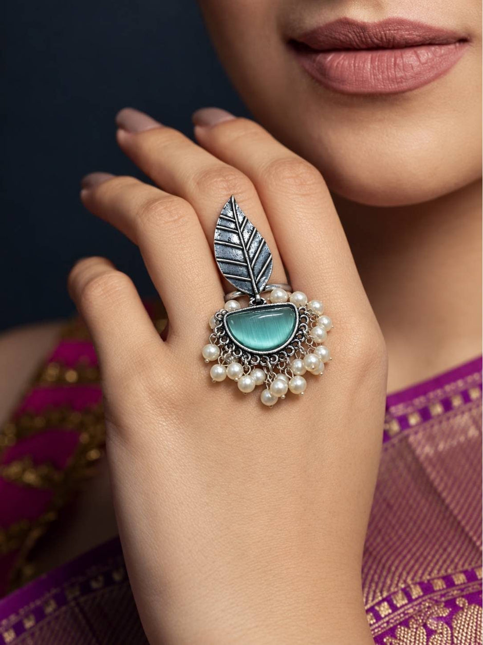 Oxidised silver leaf ring worn on middle finger against purple silk saree with pearl drops visible